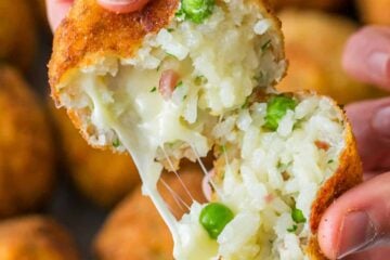 Arancini rice ball open to a cheesy center