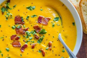 Creamy Carrot Soup in white bowl garnished with bacon