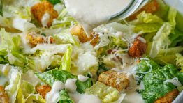 Creamy Caesar Dressing recipe poured over Caesar salad