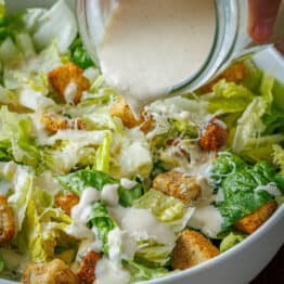 Creamy Caesar Dressing recipe poured over Caesar salad