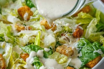 Creamy Caesar Dressing recipe poured over Caesar salad