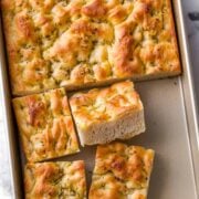 sliced focaccia bread with herbs on a metal pan