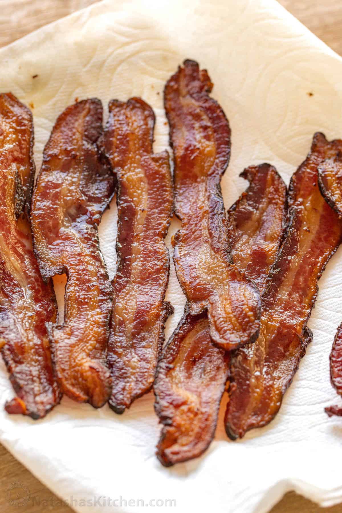 How to bake bacon in the oven that is perfectly crispy. Oven-baked bacon is the best for making a bigger batch and it's the easiest method. crispy oven-baked bacon on a plate lined with paper towel