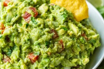 Guacamole served in a white bowl with a tortilla chip