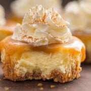 A bite taken out of a mini cheesecake cupcake with caramel sauce