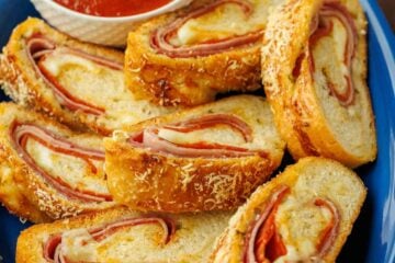 Stromboli sliced into pinwheels on a plate with marinara dipping sauce in a ramekin