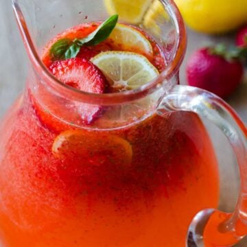 Strawberry Lemonade in a pitcher garnished with strawberries and lemon