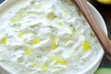 Tzatziki sauce served in white bowl with spoon