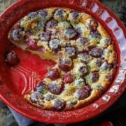 Cherry Clafoutis in a red dish with powdered sugar