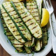 grilled zucchini on a plate with lemon slices