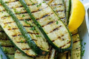 grilled zucchini recipe on a plate with lemon slices and a fork