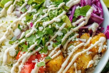 Easy Fish Taco Bowls using seasoned fish, cabbage, cilantro lime rice, cilantro, tomatoes and Fish Taco Sauce