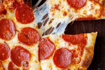 A slice pulled from a whole pizza using homemade sourdough pizza dough