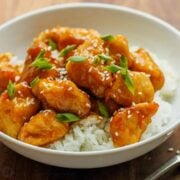 Honey Garlic Chicken cubed and served over white rice, topped with sesame seeds and green onion.