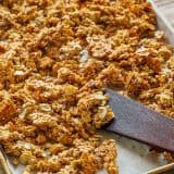 Homemade granola on a baking sheet with a spatula
