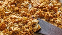 Homemade granola on a baking sheet with a spatula