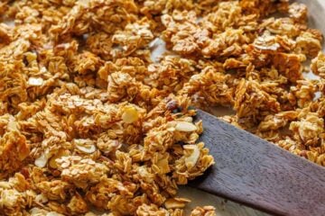 Homemade granola on a baking sheet with a spatula