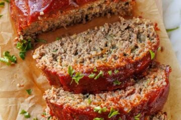 Juicy sliced meatloaf on a cutting board garnished with parsley