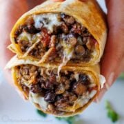 A Beef Burrito cut in half, stacked to showcase the ground beef, beans melted cheese, and tomatoes.