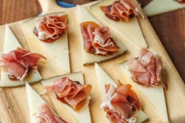Manchego Cheese Bites on a cutting board with fig spread in the background