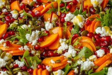 pouring dressing from a glass jar onto the persimmon salad