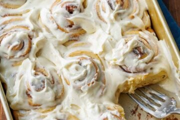 Sourdough cinnamon rolls frosted in a baking pan with 1 cinnamon roll removed