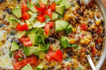 Mexican Ground Beef and Rice Skillet garnished with fresh diced tomatoes, avocado, and cilantro. Ready to serve with a spoon.