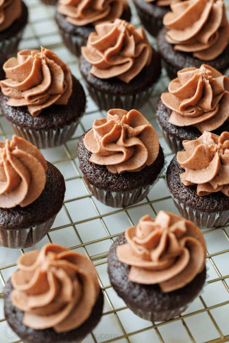 Mini Chocolate Cupcakes topped with piped Chocolate Buttercream frosting on a metal cooling rack