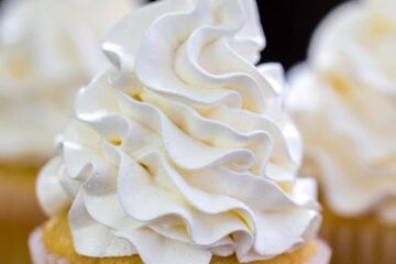 White Vanilla buttercream frosting piped onto a yellow cake cupcake