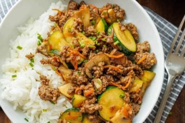 Easy Ground beef stir fry in a white bowl with a fork and tea towel