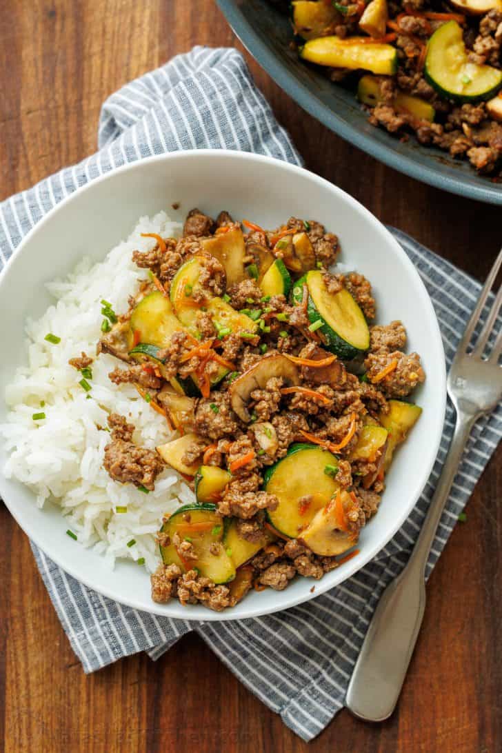 Easy Ground beef stir fry in a white bowl with a fork and tea towel