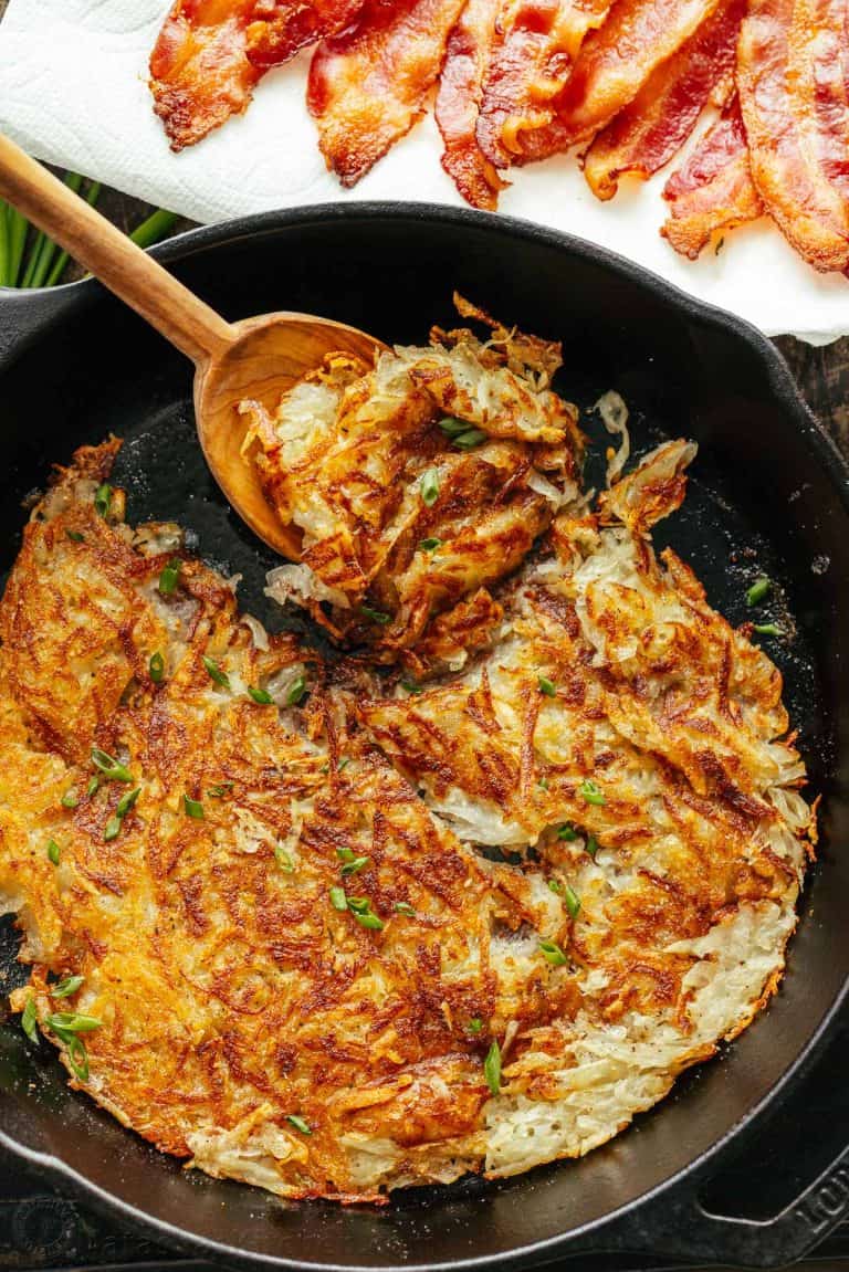 Hash browns in a cast iron skillet with a serving spoon