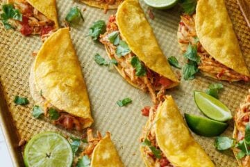 Baked Chicken Tacos on a cooking sheet with lime slices