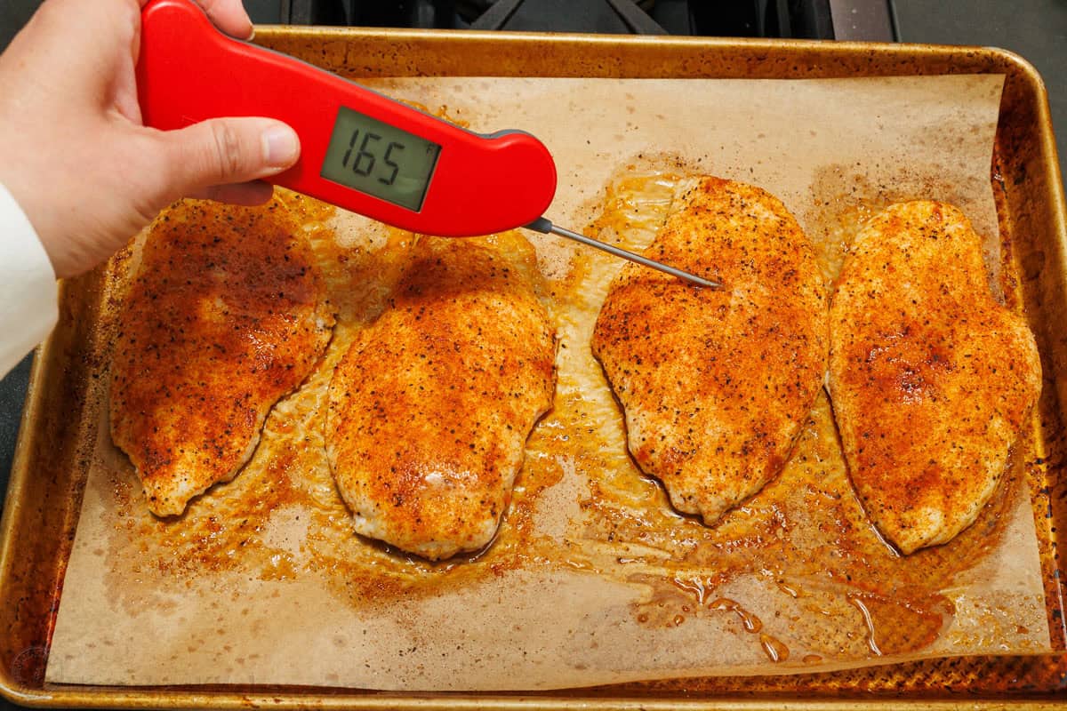 Checking internal temperature of baked chicken with thermometer