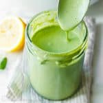 Homemade Green Goddess Dressing in a mason job and dripping from a spoon