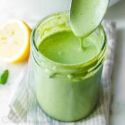Homemade Green Goddess Dressing in a mason job and dripping from a spoon
