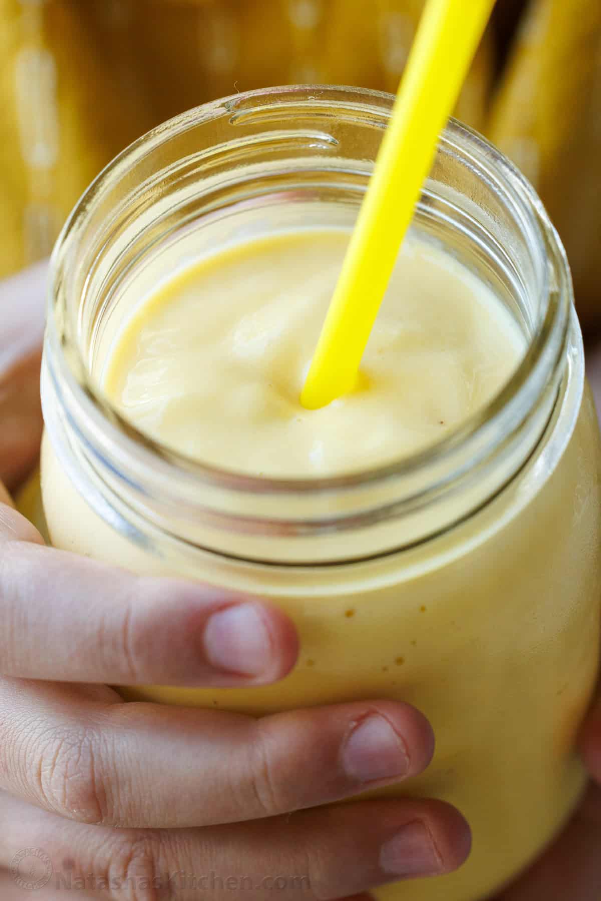 Mango Lime breakfast smoothie in a mason jar with a yellow straw