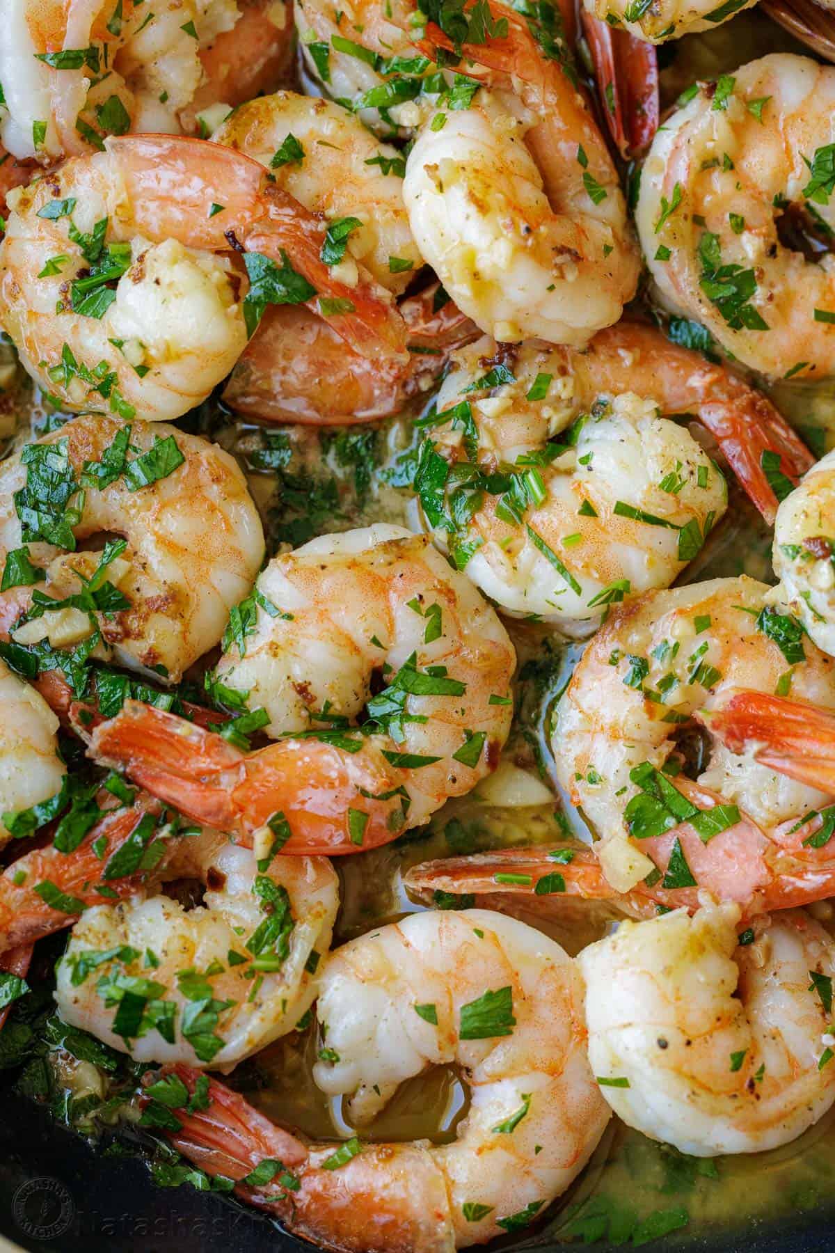 Up close shrimp scampi in a lemon-garlic butter sauce with parsley garnish.