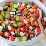 Classic Greek salad with feta, tomatoes, cucumbers, and olives tossed in Greek salad dressing in a white bowl