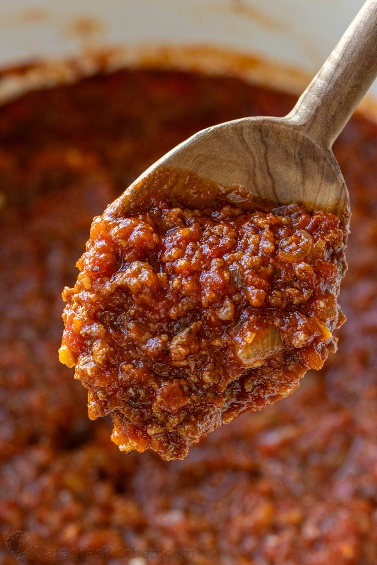 Spoon with easy spaghetti sauce with meat over a pot of sauce