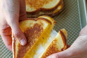 Two oven-toasted sandwiches on a cookie sheet cut in half