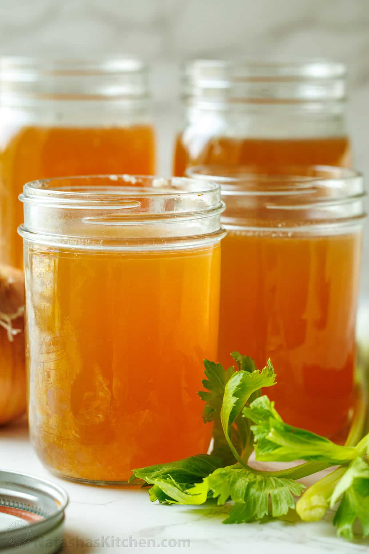 Easy homemade beef stock recipe in the slow cooker, stovetop or Instant Pot. This beef bone broth is healthy and flavorful! Boost any recipe. Four mason jars of homemade beef stock with parsley garnish
