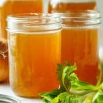 homemade beef stock recipe in mason jars with greens as garnish