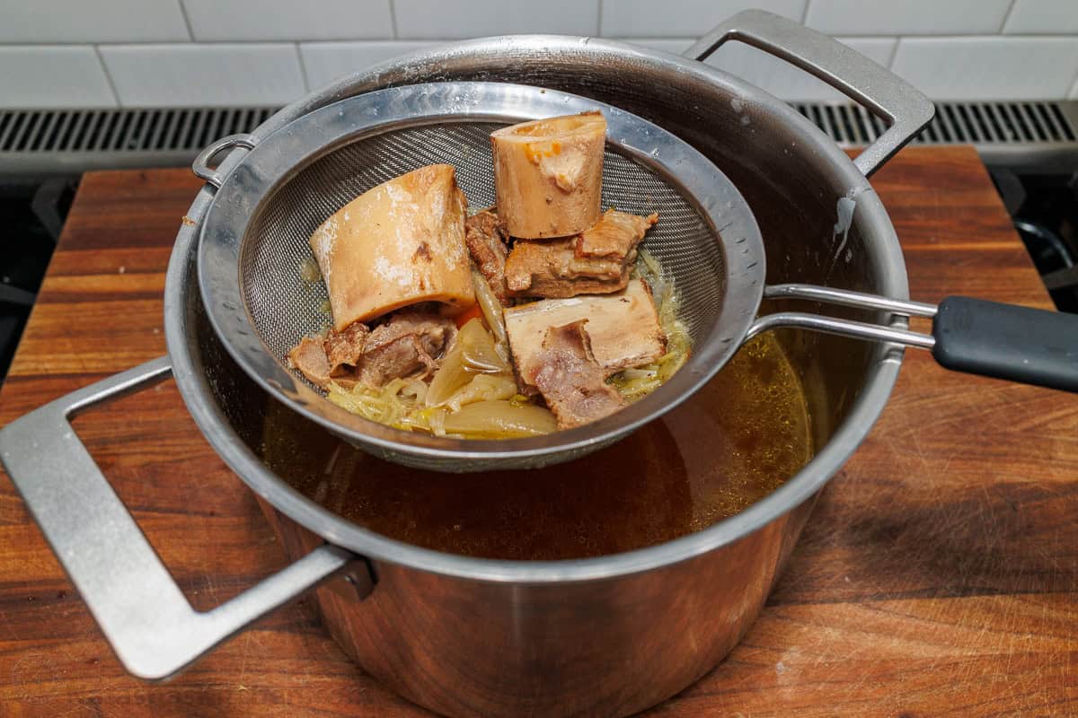 Make this easy beef stock in the slow cooker, stovetop, or Instant Pot. This beef bone broth is rich in flavor and better than store-bought. Straining beef bones and vegetables for beef stock