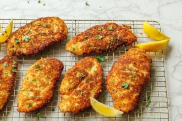 Crispy Italian Chicken Cutlets on a wire rack served with lemon wedges.