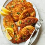 Easy Chicken Cutlets recipe on a white plate with lemon slices to garnish