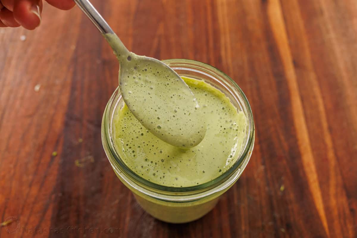 This easy Green Goddess Salad recipe comes together in minutes for the perfect side dish or lunch. Eat with a tortilla chip for a fun twist! A spoon scooping Green Goddess Dressing out of a mason jar