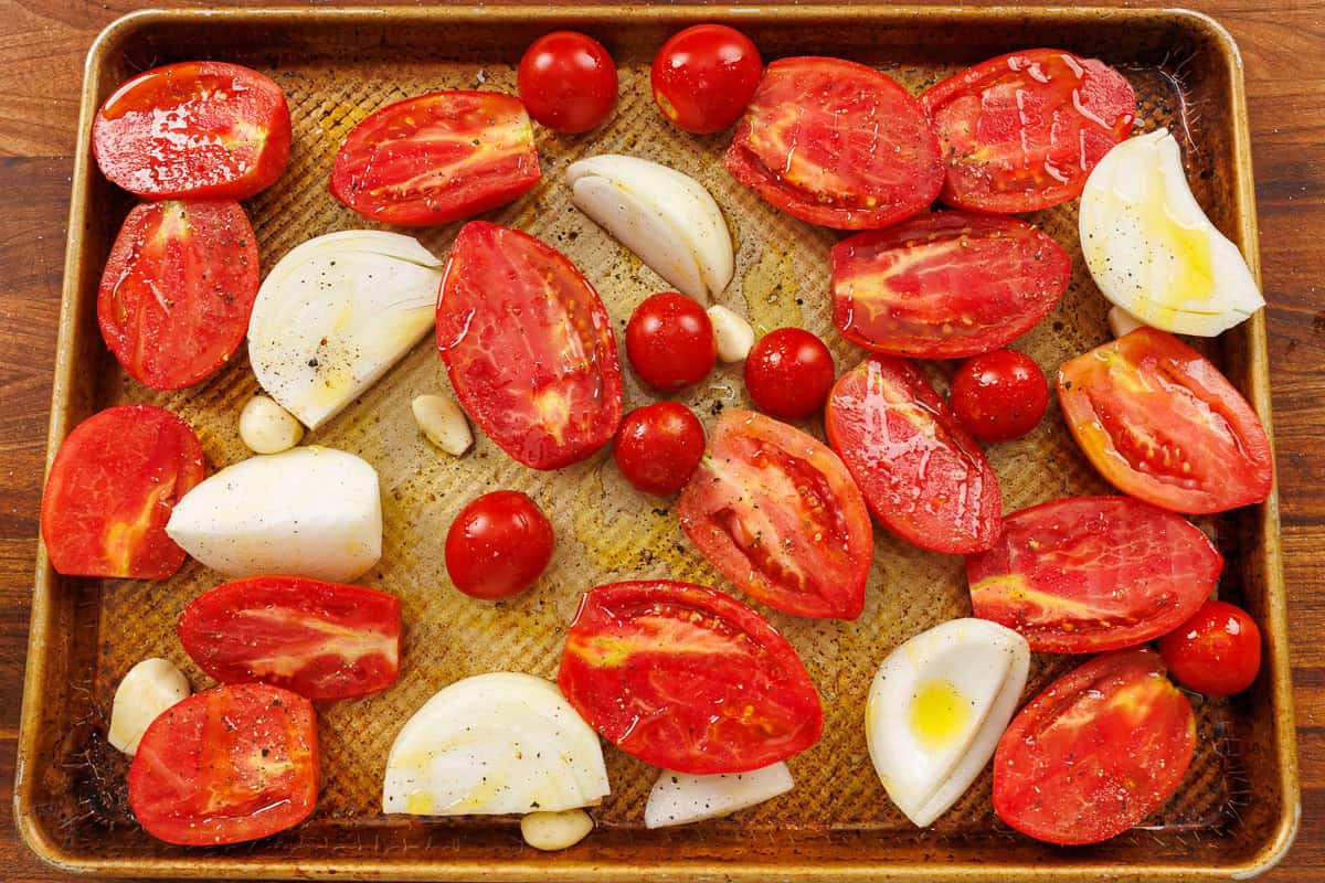 Roasted tomato soup has layers of delicious flavor for a creamy satisfying and easy dish. Pair with Grilled Cheese for the best Fall recipe. Tomatoes and onions on a sheet pan for roasting