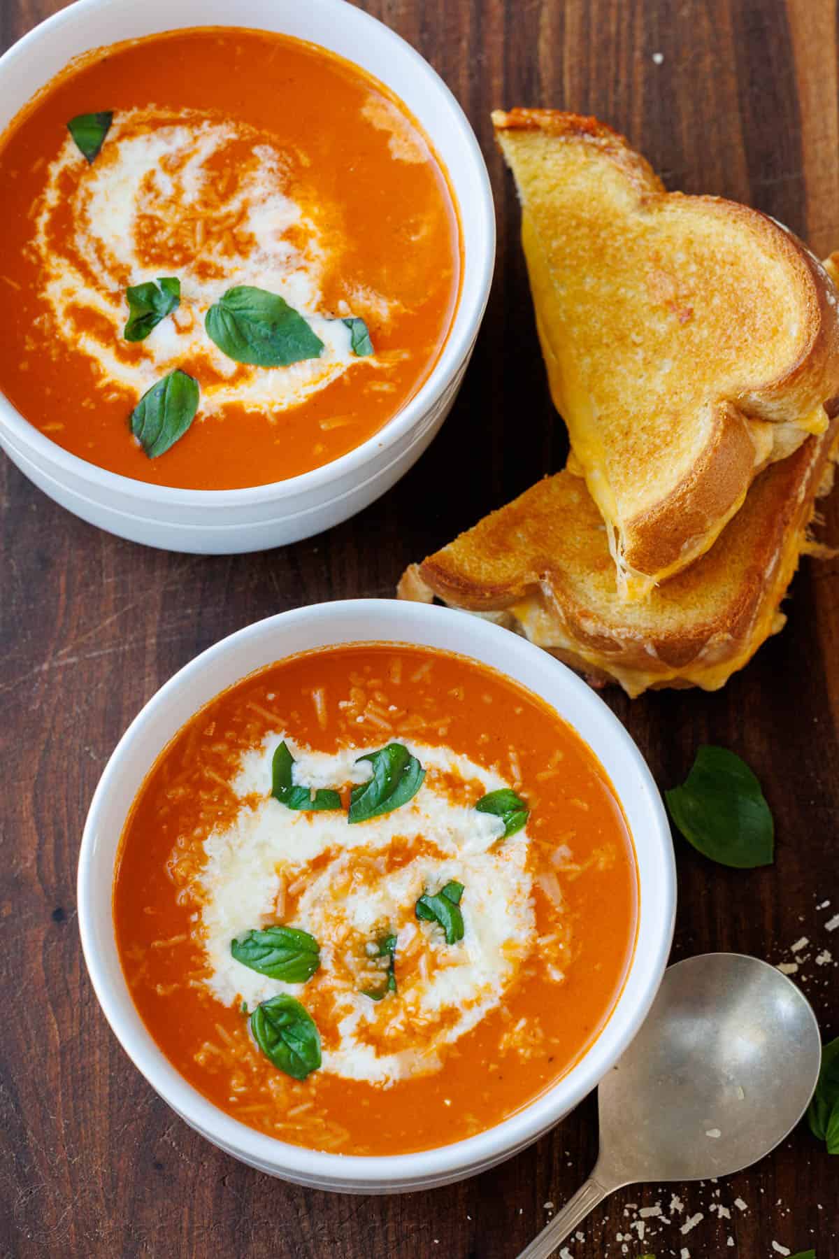 Roasted tomato soup has layers of delicious flavor for a creamy satisfying and easy dish. Pair with Grilled Cheese for the best Fall recipe. Nostalgic childhood dinner of Grilled Cheese served with bowls of Homemade Tomato soup on a wooden table