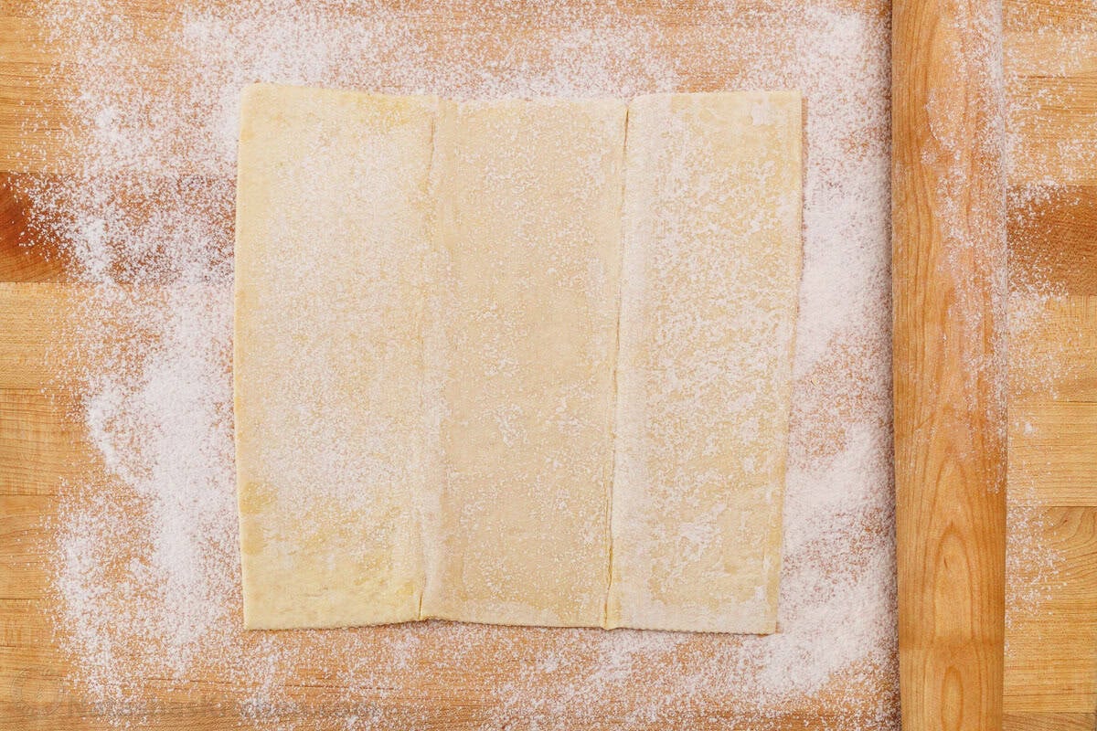 Puff pastry on a butcher block with flour dusted on the top